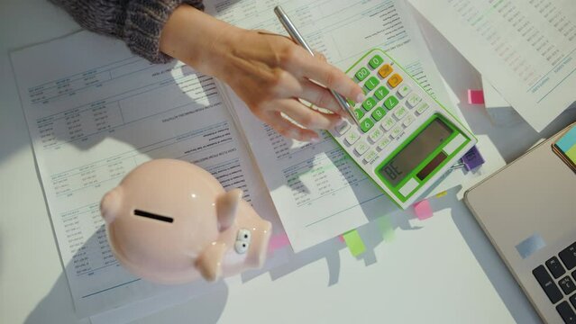 tax time. piggy bank and accountant woman with calculator and documents working in office.