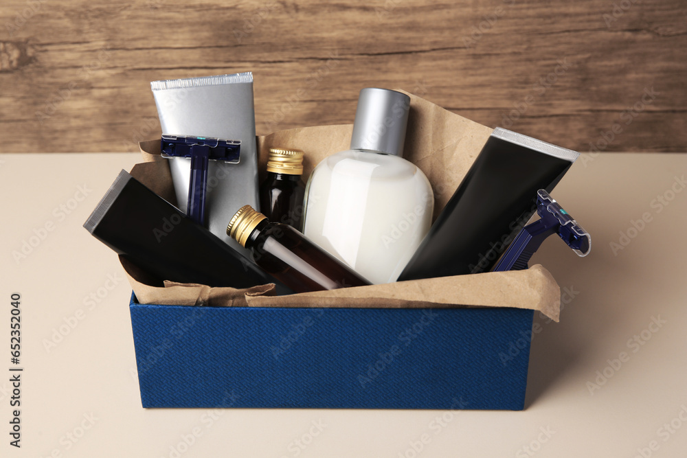 Wall mural box with different men's shaving accessories and cosmetics on beige table