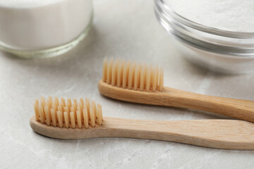 Bamboo toothbrushes and baking soda on light marble table