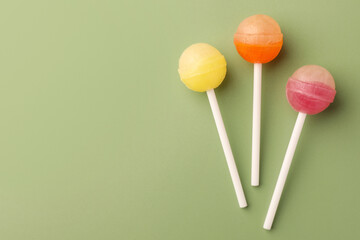 Tasty lollipops on green background, flat lay. Space for text