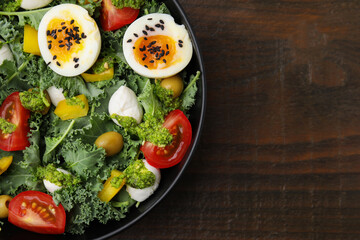 Delicious salad with pesto sauce in bowl on wooden table, top view. Space for text