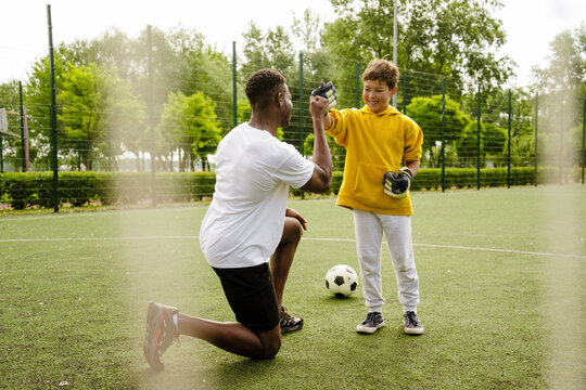 African man and his son giving fist bump while standing on football field