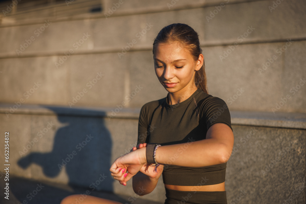 Wall mural Teen Girl Looking On Smart Watch Before Training Outdoor