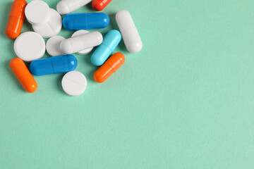 Pile of colorful pills on green background, above view. Space for text