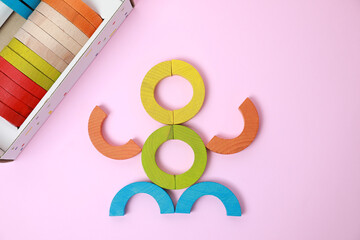 Colorful wooden pieces of playing set on pink background, flat lay. Educational toy for motor...