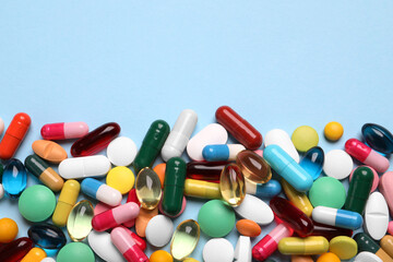 Many different pills on light blue background, flat lay. Space for text