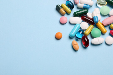 Many different pills on light blue background, above view