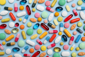 Many different pills on light blue background, flat lay