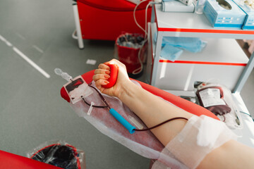 Young woman making blood donation in hospital. A woman donates blood while holding a red heart....