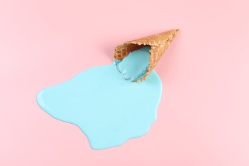 Melted ice cream and wafer cone on pink background, top view
