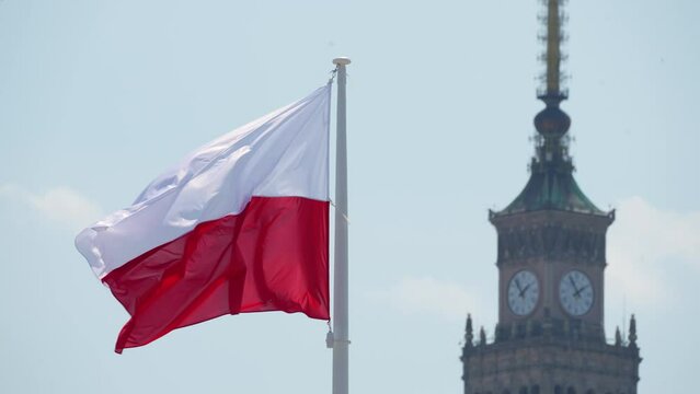 Close up view Flag of Poland or Polish Flag waving at wind against beautiful blue sky and Palace of Culture and Science. Warsaw