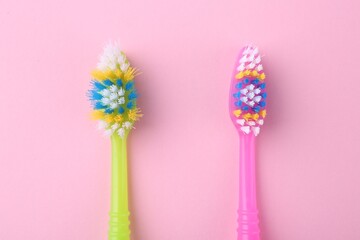Colorful plastic toothbrushes on pink background, flat lay