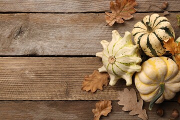 Fototapeta premium Fresh ripe pumpkins and dry leaves on wooden table, flat lay. Space for text