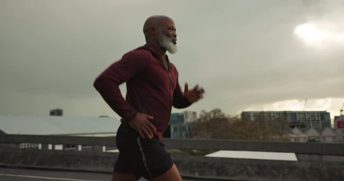 Senior African man, running and city in street, morning and vision for fitness, health and profile in retirement. Elderly runner, urban road and training with exercise, freedom or bridge in Cape Town