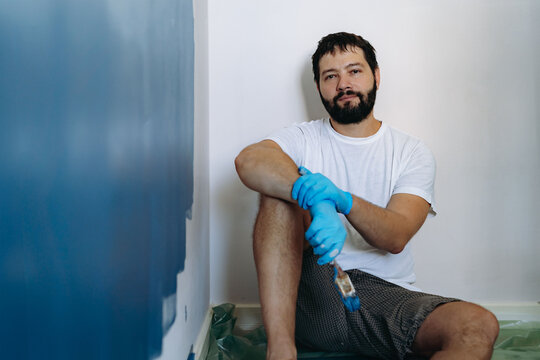 home renovation. caucasian bearded man having rest after painting wall