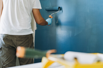 caucasian bearded man painting wall with paint roller. Painting apartment, renovating home - obrazy, fototapety, plakaty