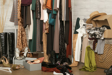 Untidy cluttered woman wardrobe with stylish clothes and accessories. Messy clothes thrown on a...