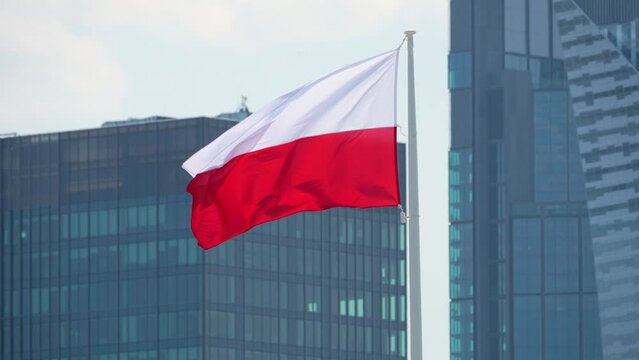 Close up Flag of Poland or Polish Flag waving at wind against downtown glass skyscrapers urban skyline