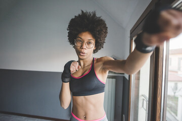 Young multiethnic woman at home training doing boxe exercise - obrazy, fototapety, plakaty