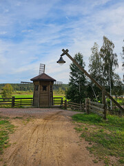 an old wooden mill in the village against the background of a green forest, a lantern on a wooden pole, photo