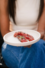 Woman holding plate of tuna sashimi at a restaurant in Australia