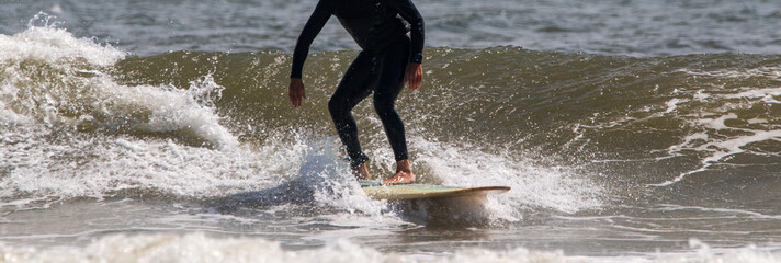 Man wearing a black wetsuit surfing in the ocean