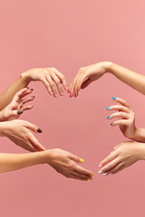 Heart shape. Beautiful female hands with different manicure, nail colors against pink background. Taking care. Concept of hand care, cosmetics and cosmetology, spa, natural beauty. Poster, ad