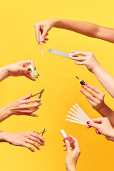 Female hands holding different tools for manicure against yellow background. Nail polish, cuticle...