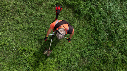 High angle view of modern gardener mows the grass with lawn mower.