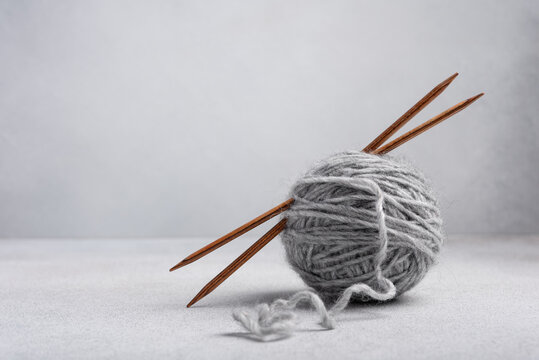 Gray clew of yarn with wooden knitting needles