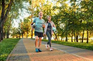 Full length image of beautiful sporty healthy active cheerful middle age couple going to exercise...