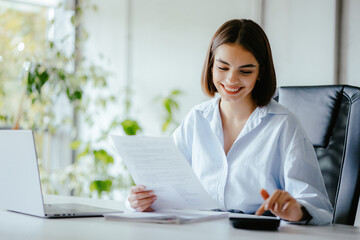 Accountant woman doing work at her desk with paper and calculator.