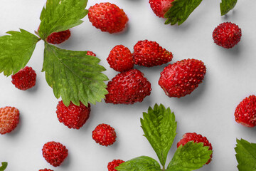 Many fresh wild strawberries and leaves on white background, flat lay