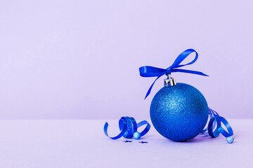 Christmas ball on colored background. decoration bauble with ribbon bow with copy space