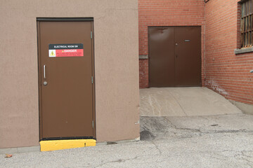 electrical room sw danger arc flash and shock hazard appropriate ppe required sign on brown metal full entrance door and others next to it