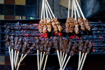 Sate Maranggi, traditional cuisine originated from West Java, Indonesia. It is bamboo-skewered marinated beef/chicken, grilled in charcoal flame. Dark grainy (noise) concept. - obrazy, fototapety, plakaty