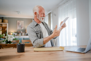 senior caucasian man open mail letter or document envelope at home