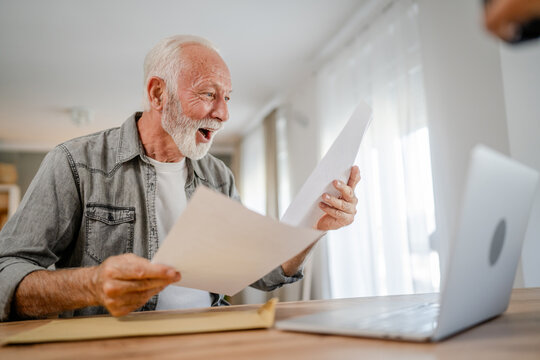 senior caucasian man open mail letter or document envelope at home