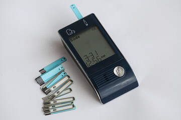 Blood glucose meter and hand, blood sugar measurement. The concept of measuring blood sugar for diabetics. White background, selective focus.