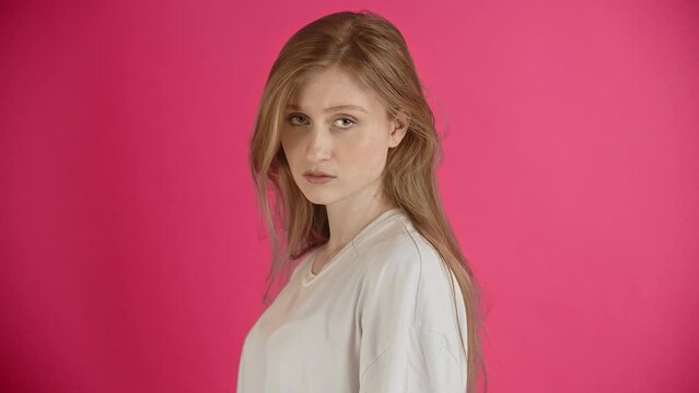 Girl in emotions of disappointment and annoyance. A young lady with sad and offended gaze look at camera disapprovingly and shows a frightening fist gesture. Wants to punish for disobedience or pain