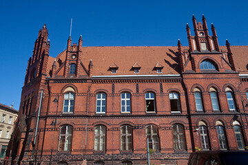 Fototapeta na wymiar Zabytkowy budynek poczty zbudowany w stylu neogotyckim, z elewacją frontową o wielu sterczynach oraz wmurowanym zegarem, Grudziądz, Poland
