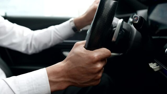 male hands on car steering wheel, closeup view, personal driver or businessman driving auto in city