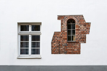 Textured natural stone wall background. light stone wall with windows with brick decor, facade of a residential building.