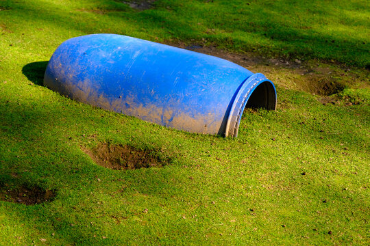A large blue plastic barrel half buried in the ground. A place for small pets to hide
