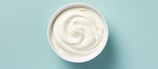 A isolated pastel background Copy space showcases a bowl of sour cream from above - obrazy, fototapety, plakaty