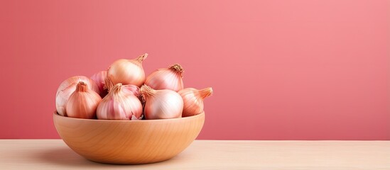 Red onions in wooden bowl on a isolated pastel background Copy space - obrazy, fototapety, plakaty