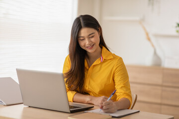 Entrepreneur beautiful business asian young woman wear yellow shirt work online with laptop at...