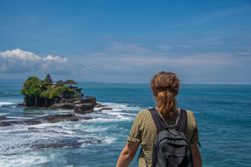 Woman with backpack looks at the "Pura Tanah Lot" temple