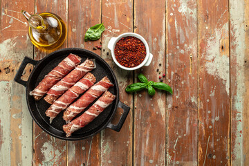 Thin bacon rolls with minced meat on a wooden board, banner, menu, recipe place for text, top view
