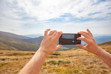 hand with phone making photo of scenic landscape of Chornohora mountain range in Ukrainian
